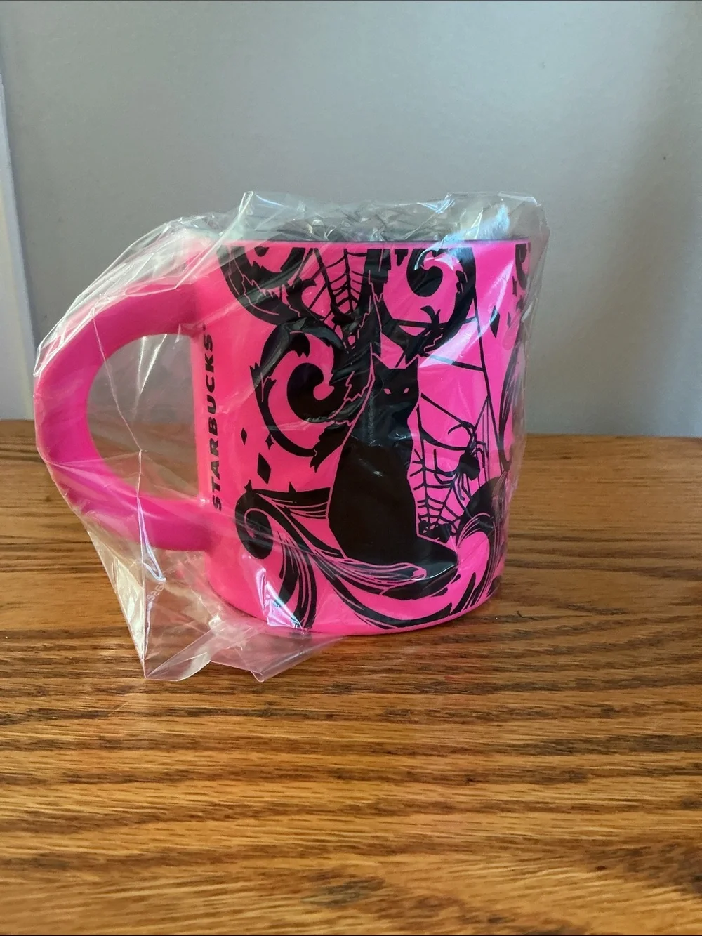 Starbucks Halloween 2021 neon pink coffee mug features a bold black cat-spider.